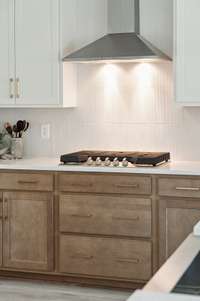 Gas cook top with drawer below are just the best for covenience while cooking. Goodwin farms has upgraded from Stainless Steel hood to painted Wood hood to match cabinets. Model home has a good example of this hood. Stop by.