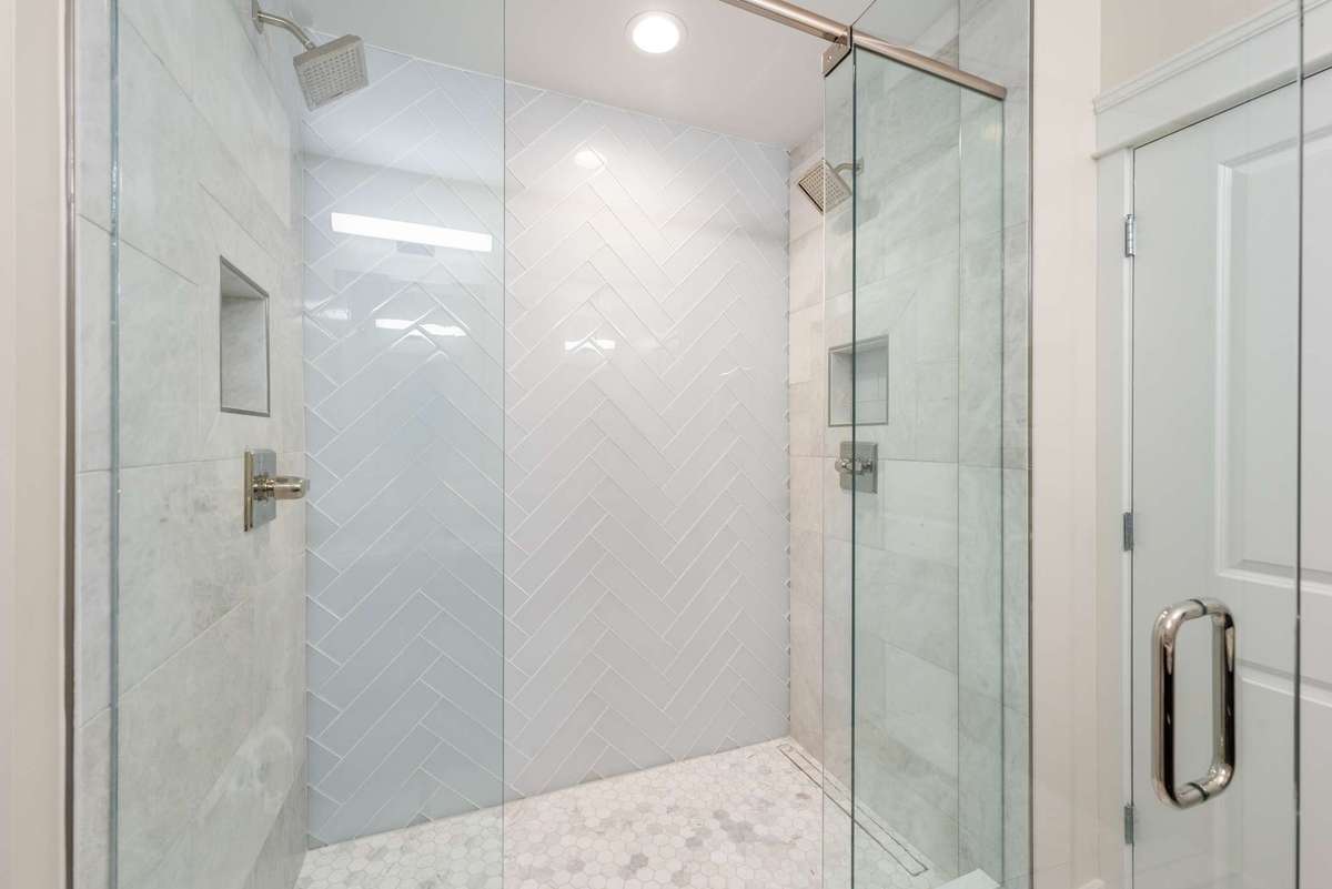 Newly renovated shower with marble tile and dual shower heads.