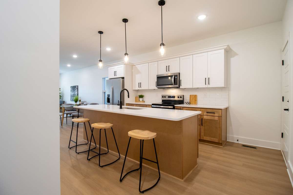 You'll enter into a sizable kitchen with modern oak-toned and white cabinetry.