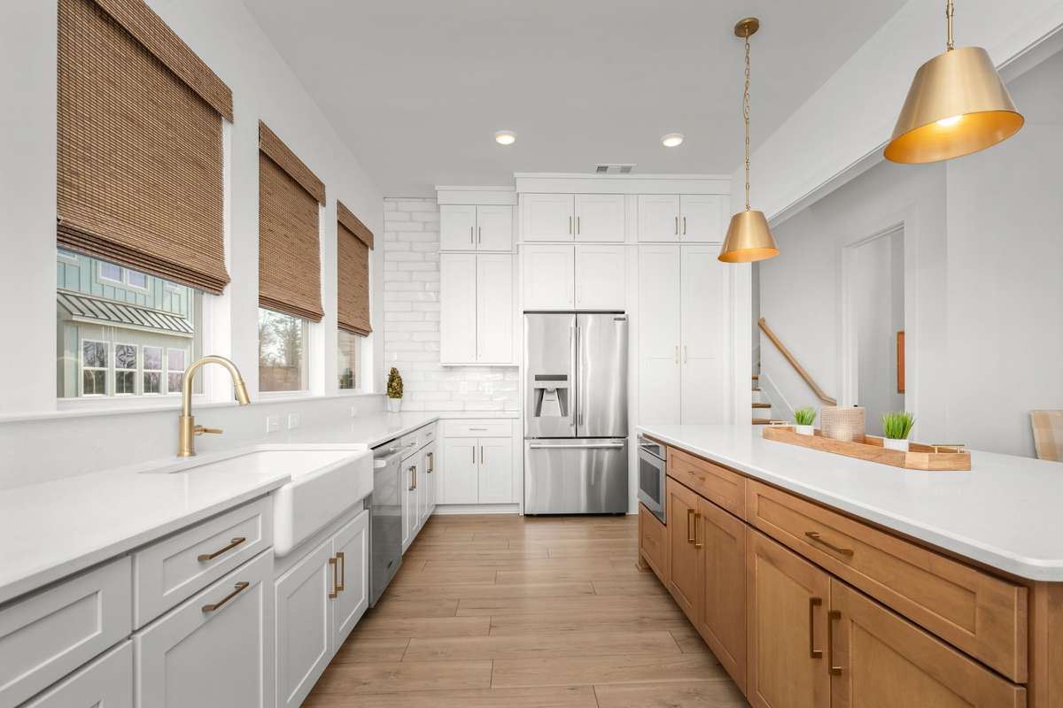 Gourmet kitchen with oversized island, quartz counters, gas range with stainless vent hood, custom backsplash, picturesque windows, and a hidden walk-in pantry!