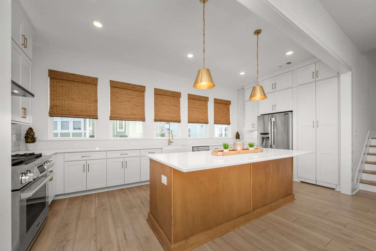 Gourmet kitchen with oversized island, quartz counters, gas range with stainless vent hood, custom backsplash, picturesque windows, and a hidden walk-in pantry!