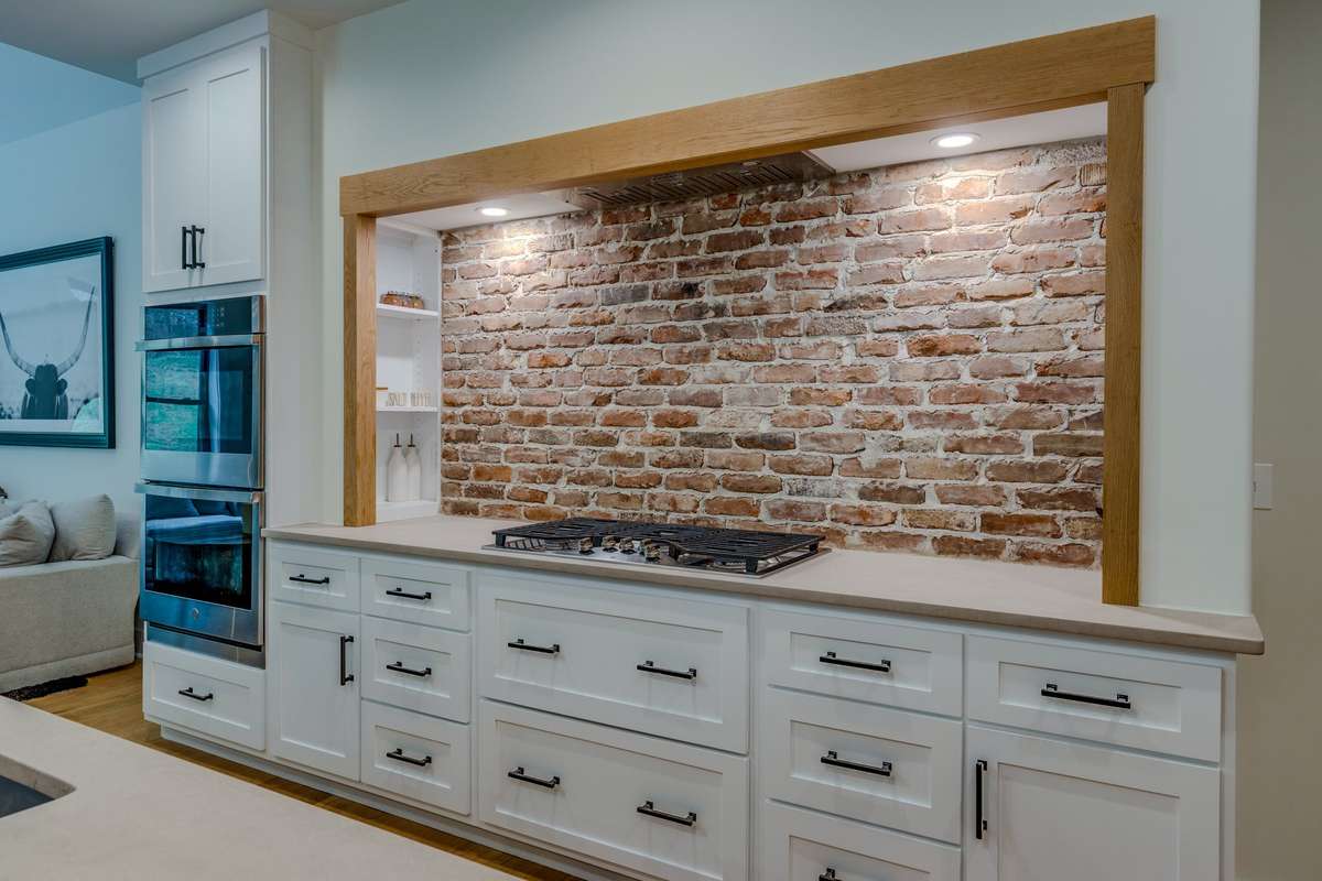 Gas cooktop with custom finished counters and brick backsplash.