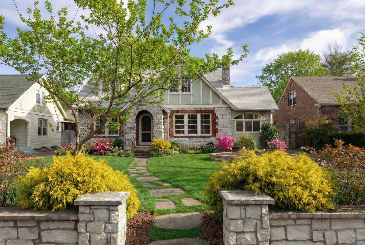 Inviting front walkway framed by lush landscaping leads to the arched stone entry, creating a warm and welcoming first impression. *Exterior landscape digitally enhanced.