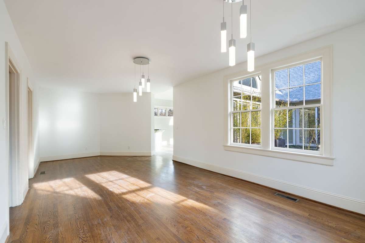 Dining room flows seamlessly toward the kitchen, with abundant natural light and updated lighting enhancing the space.