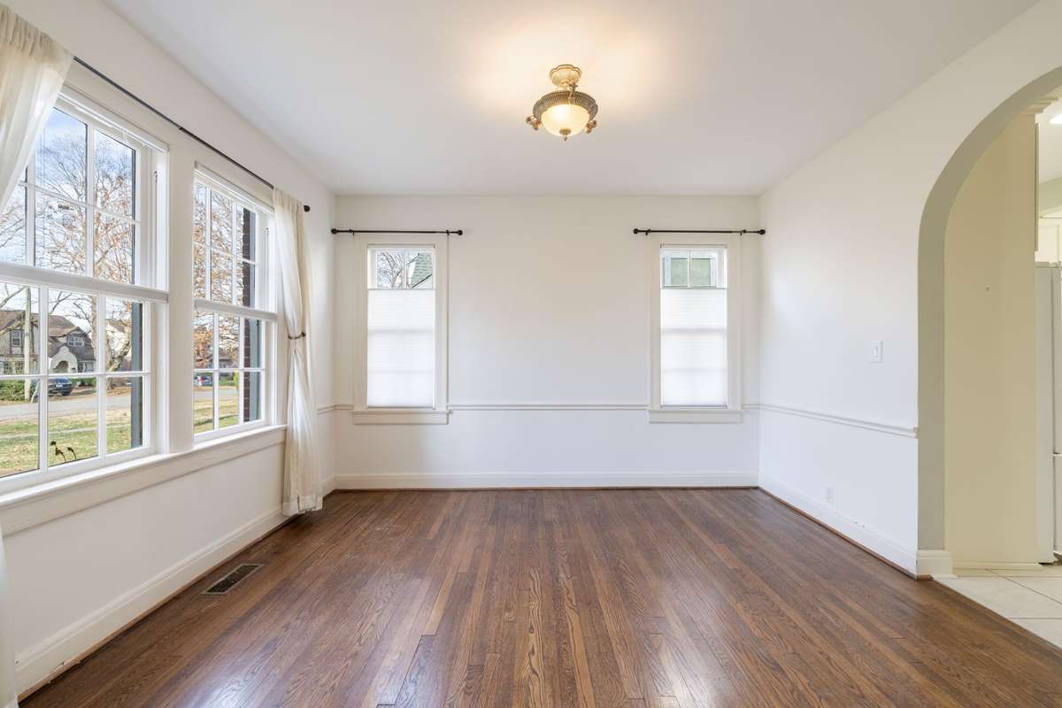 The den offers sand and finish hardwood floors, chair rail detail, and a bright, airy layout perfect for gatherings and entertaining.
