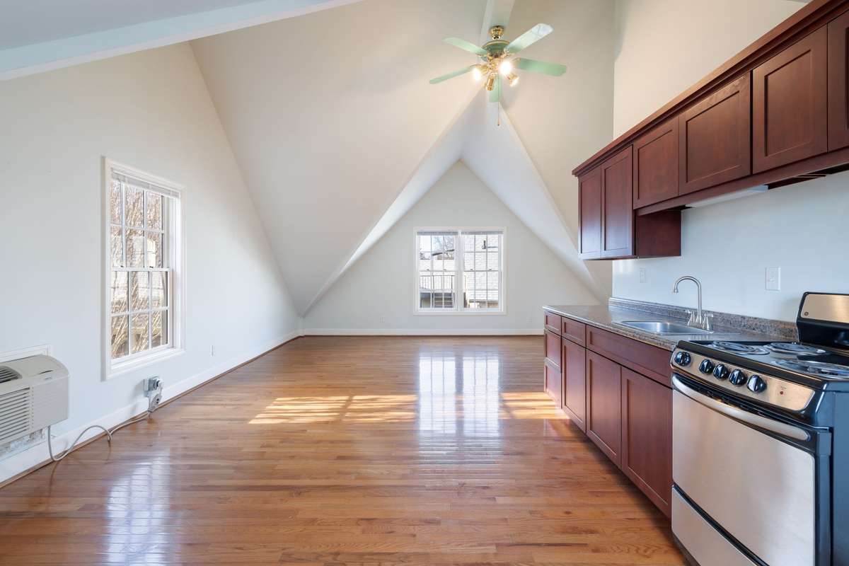 Open-concept upper-level living area featuring vaulted ceilings and hardwood flooring. Kitchen is thoughtfully positioned to maximize space and flow.