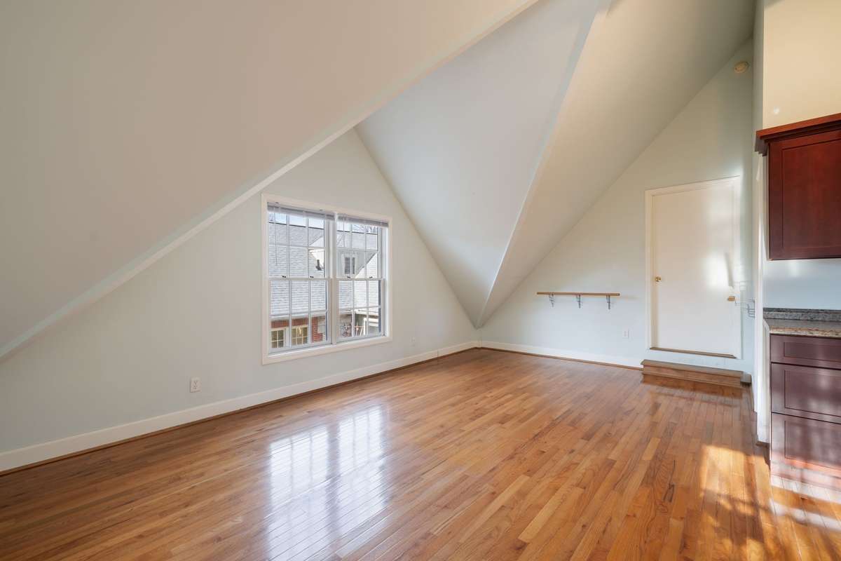 Expansive upper-level living space with dramatic vaulted ceilings and multiple windows for natural light. Offers excellent flexibility for living, dining, or workspace arrangements.