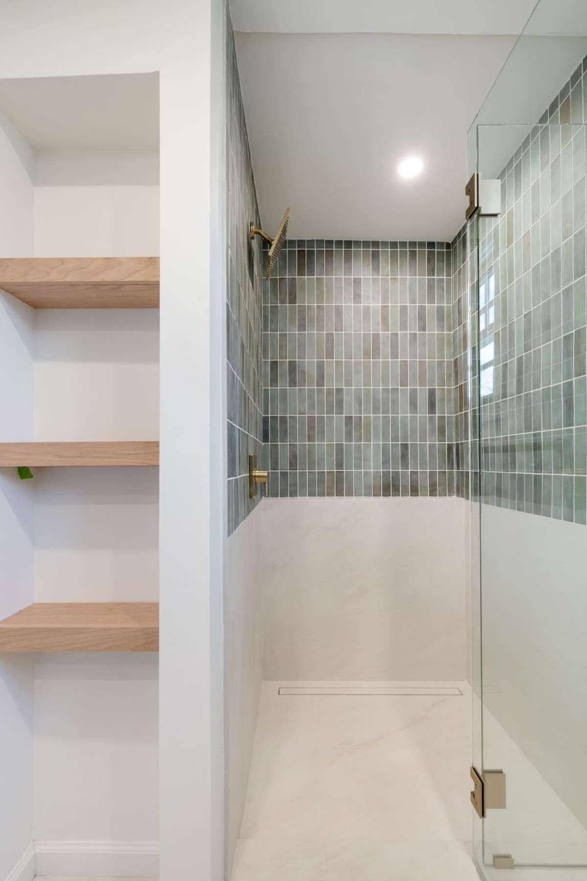 Walk-in shower showcases sleek tilework, glass enclosure, and contemporary brass hardware.
