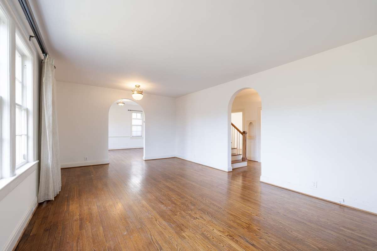 Spacious living room showcases sand and finish hardwood floors and graceful arched openings that create an easy flow between living, dining, and entry areas.