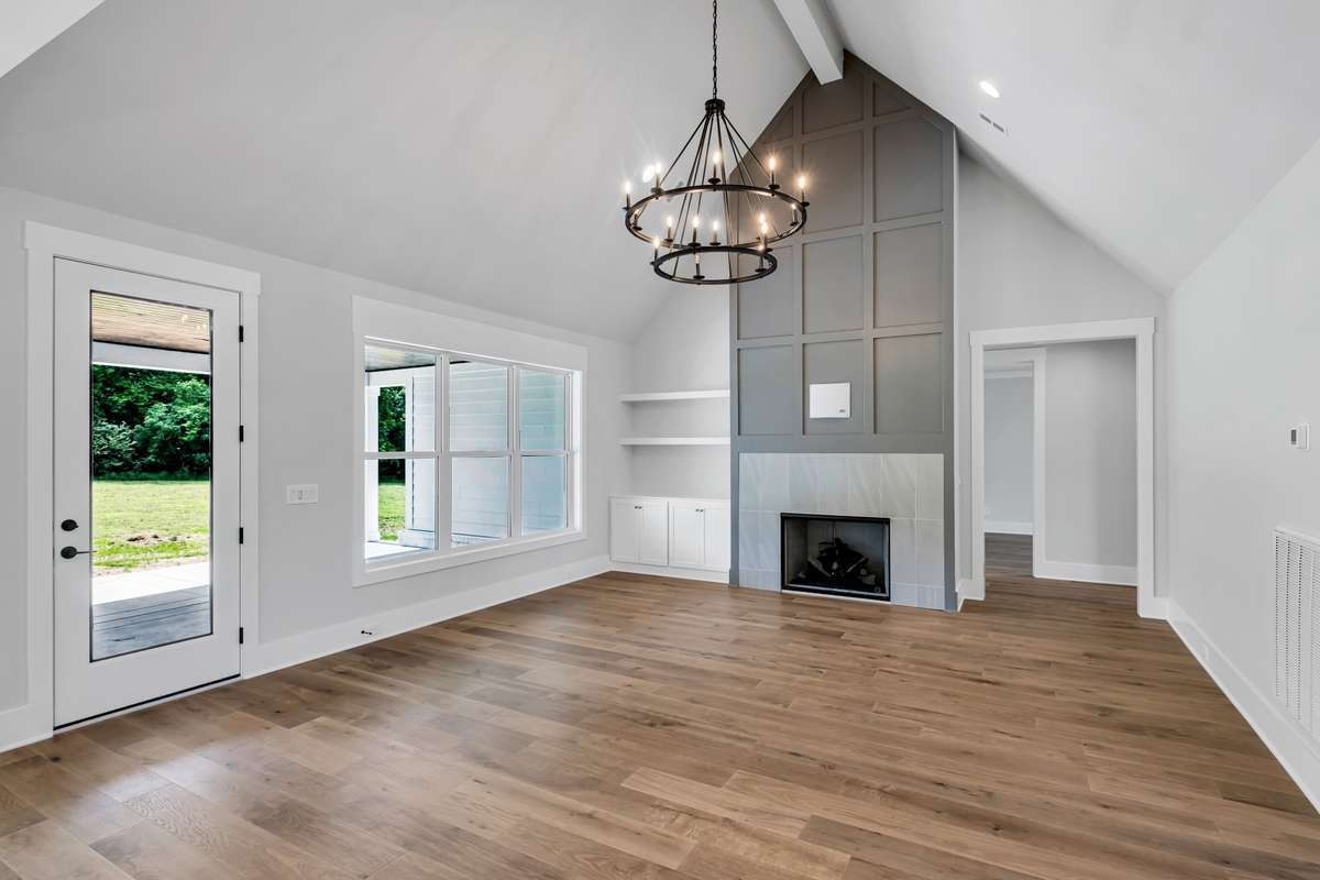 Living Room includes vaulted ceiling, hardwood flooring, trim detail or tile on fireplace, and optional/completely customizable built ins or shelving on same wall