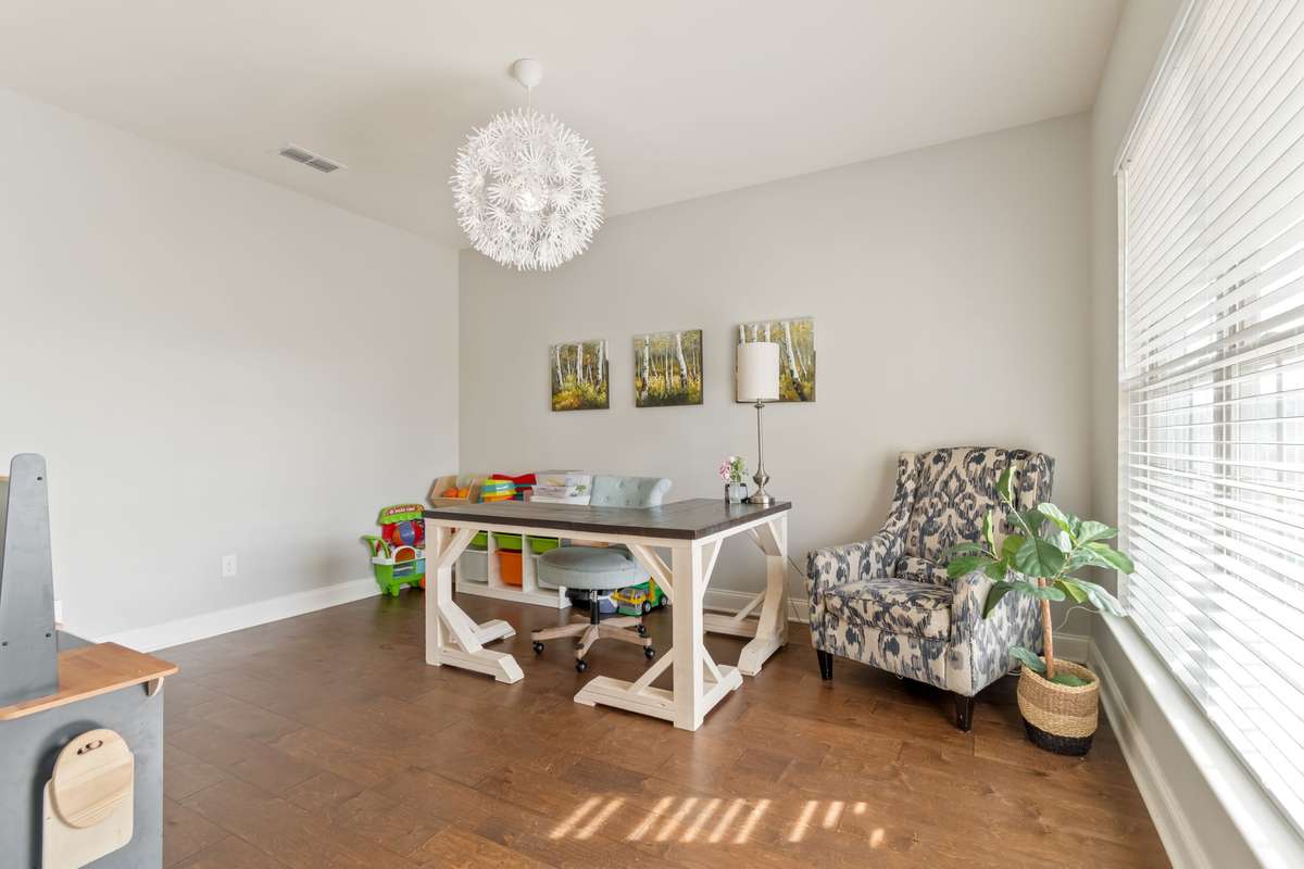 This room is currently used as an office/playroom with a large front window providing abundant light.