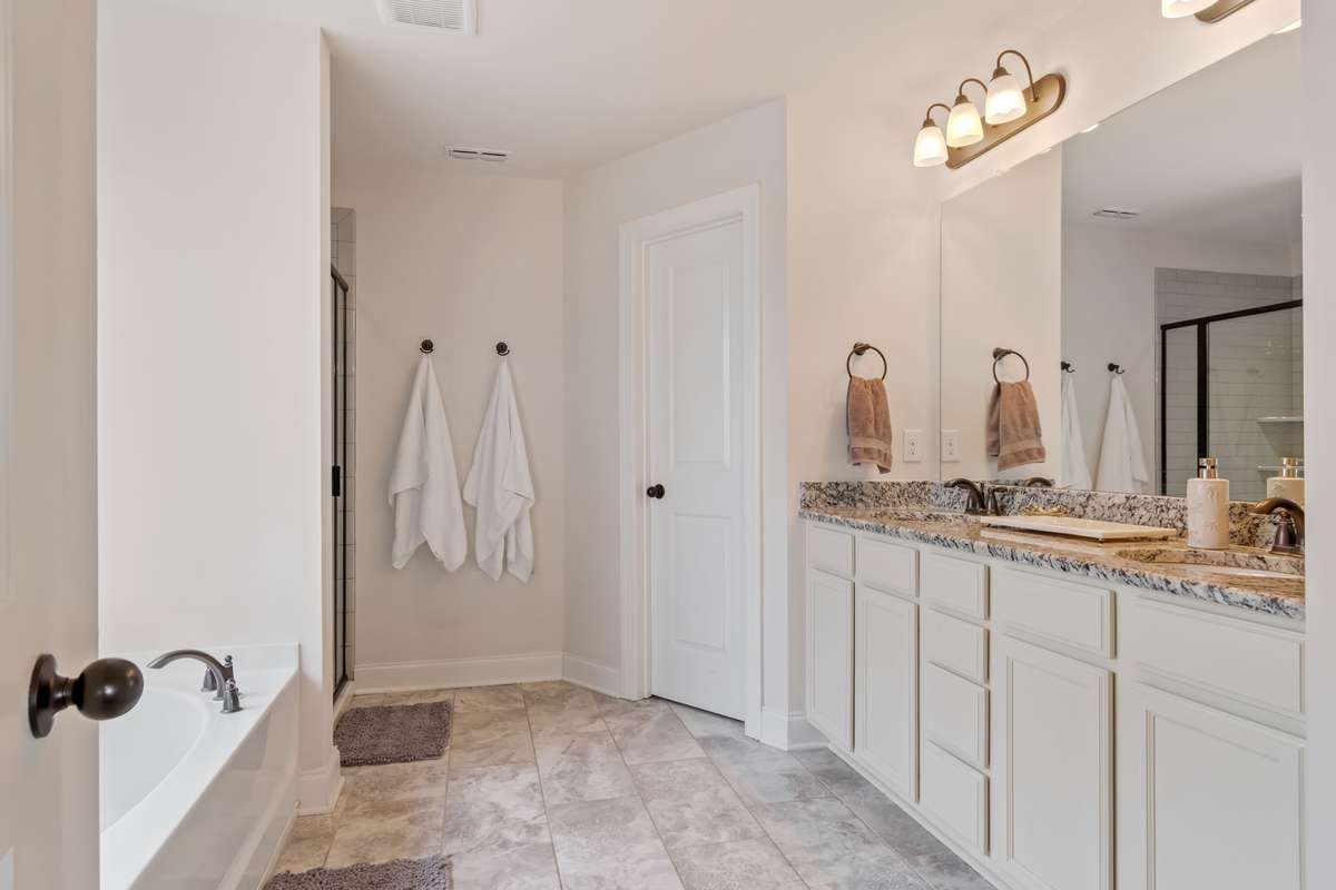 Double sinks, a soaking tub, a tiled shower, and private water closet add to the functionality of this primary bathroom.