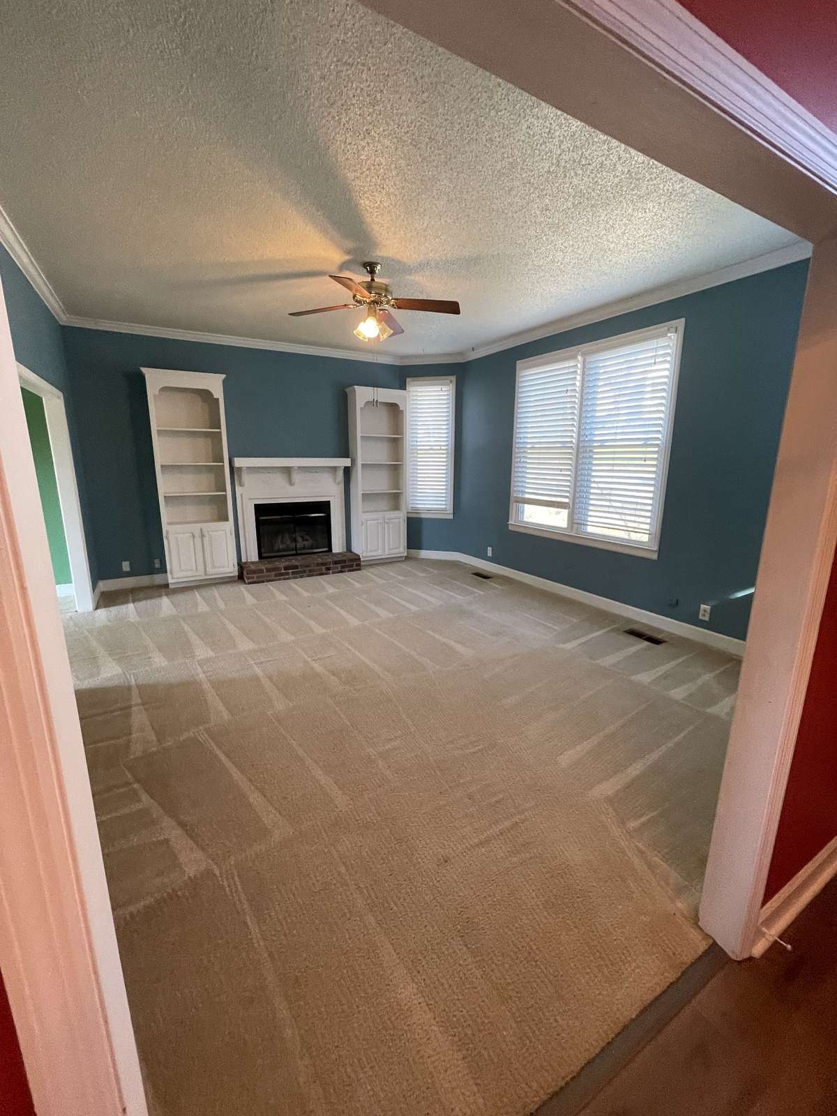 living room with fireplace, built in book shelves and beautiful large windows letting the natural light in.