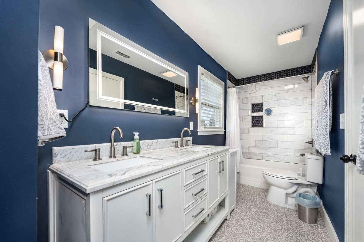 Primary ensuite bathroom has been thoughtfully updated with double vanity, marble countertop, and a tiled shower-tub combo