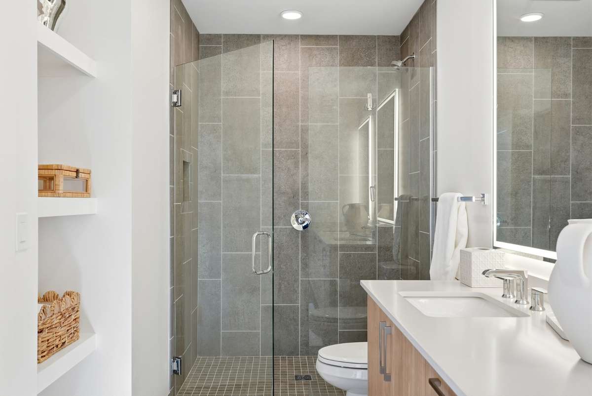 Contemporary bath featuring a walk-in glass shower, tile surround, and clean modern vanity.