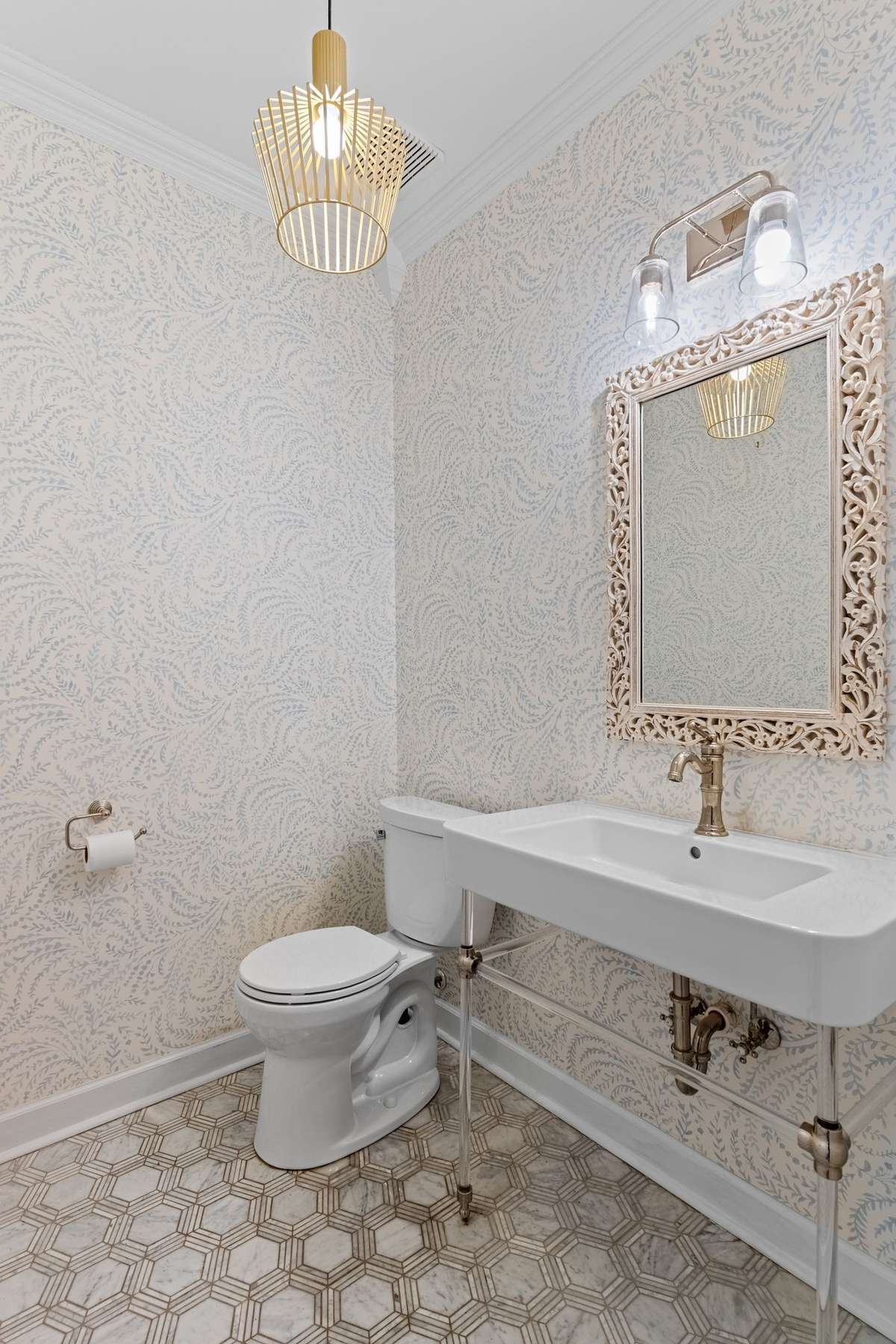 Stunning renovation of the powder room, with tile floor, pedestal sink, new mirror and lighting and wall paper.