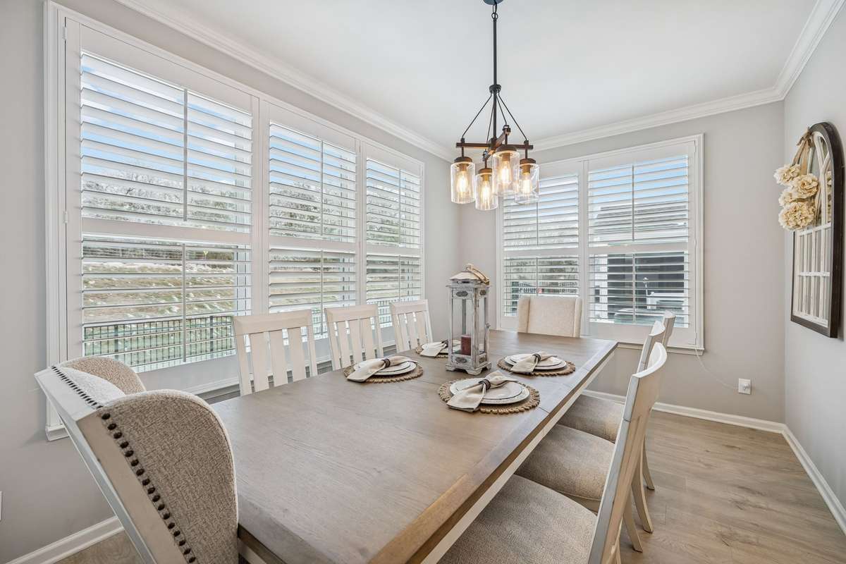 Formal dinning room with custom window treatments. Wooden built in shades. Bottom shade operates separately for privacy while allowing in natural light