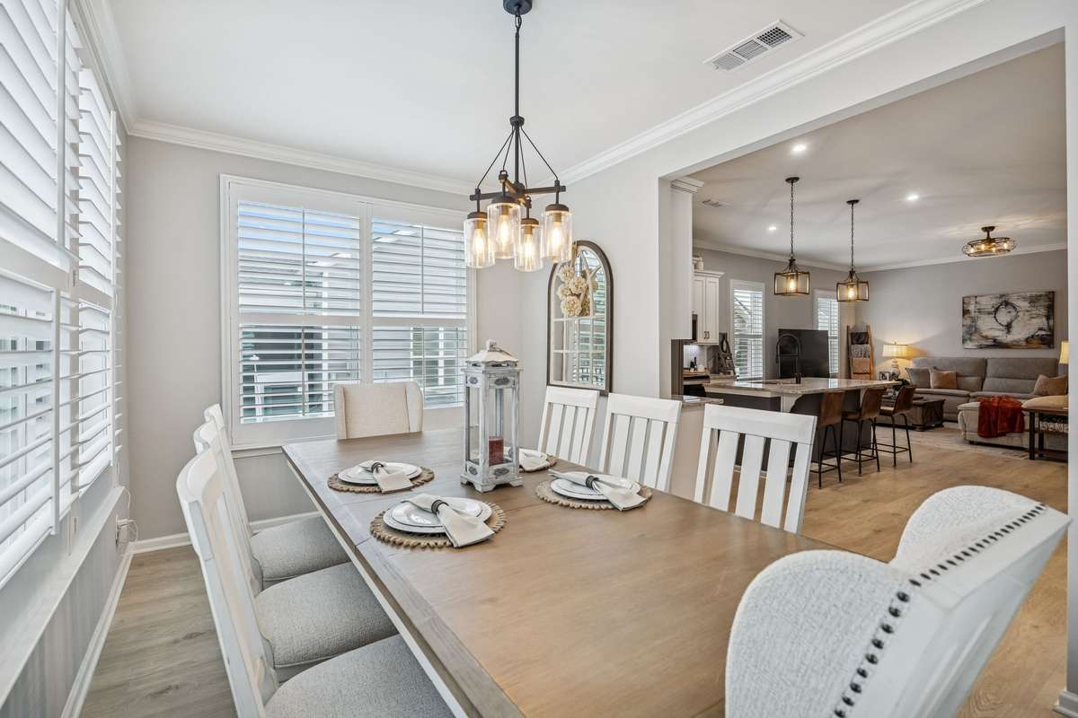 Formal dinning room with custom window treatments. Wooden built in shades. Bottom shade operates separately for privacy while allowing in natural light