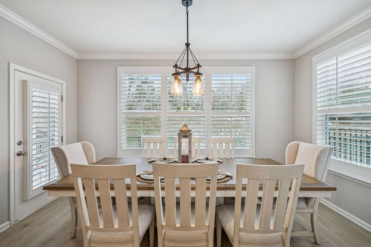 Formal dinning room with custom window treatments. Wooden built in shades. Bottom shade operates separately for privacy while allowing in natural light
