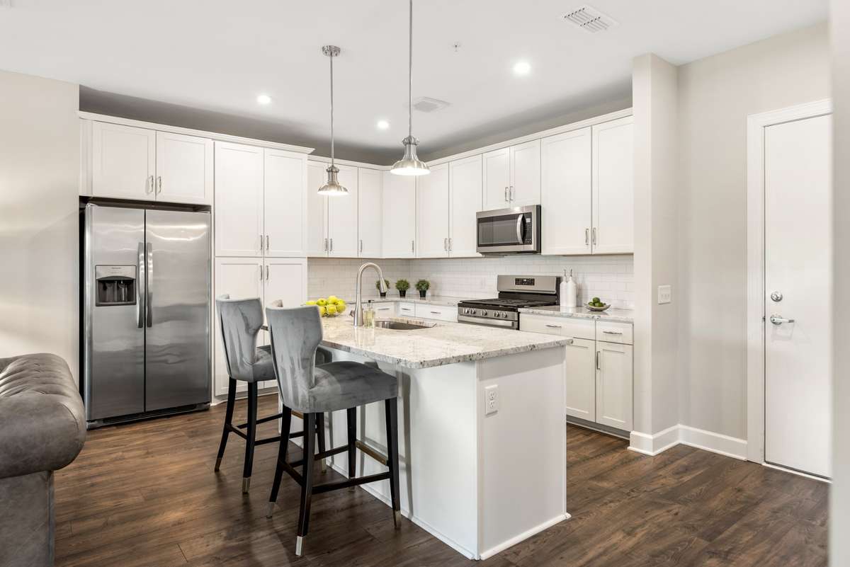 Fully equipped kitchen with stainless steel appliances, gas stove, granite countertops, subway tile backsplash, and abundant cabinet space.