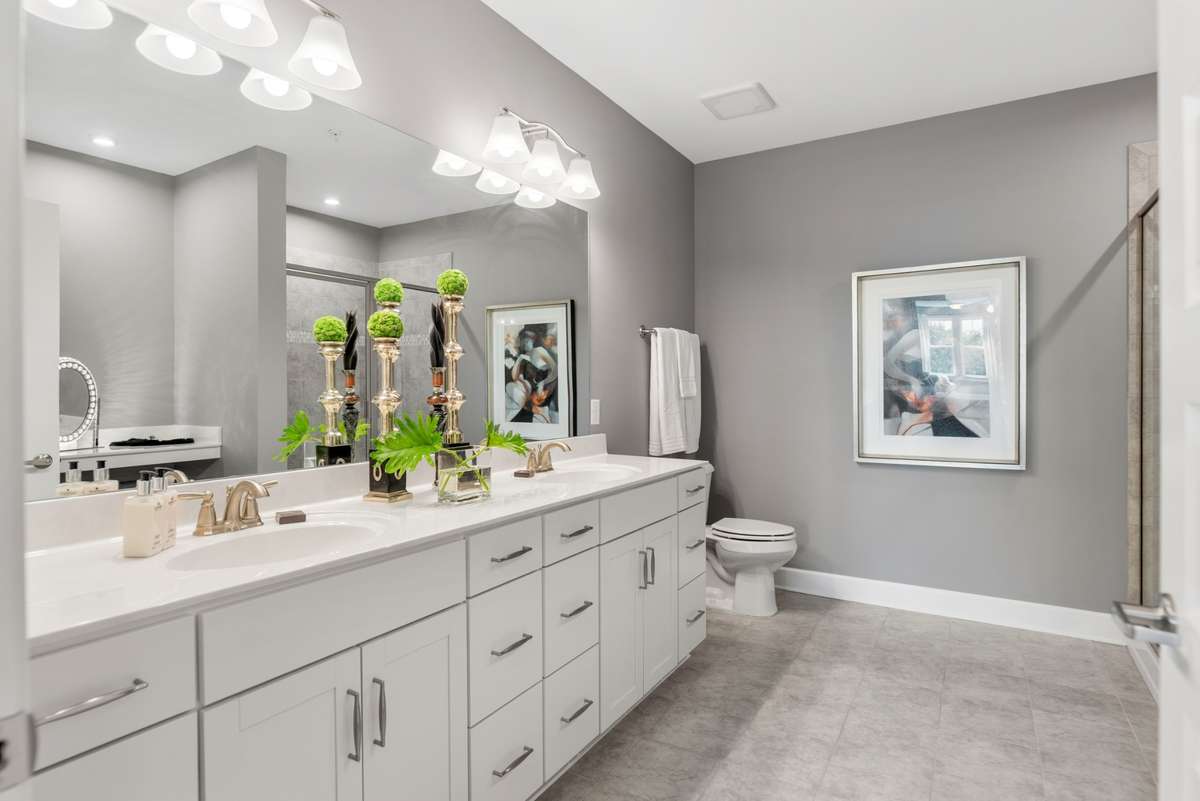 Double vanity with tons of storage, ceramic tile flooring, and a large mirror illuminated with designer lighting, creating a spa-like retreat.