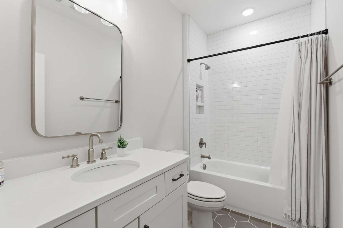 White tile backsplashes and gray schemed tile create an open and clean feel to the 2nd Full Bathroom.