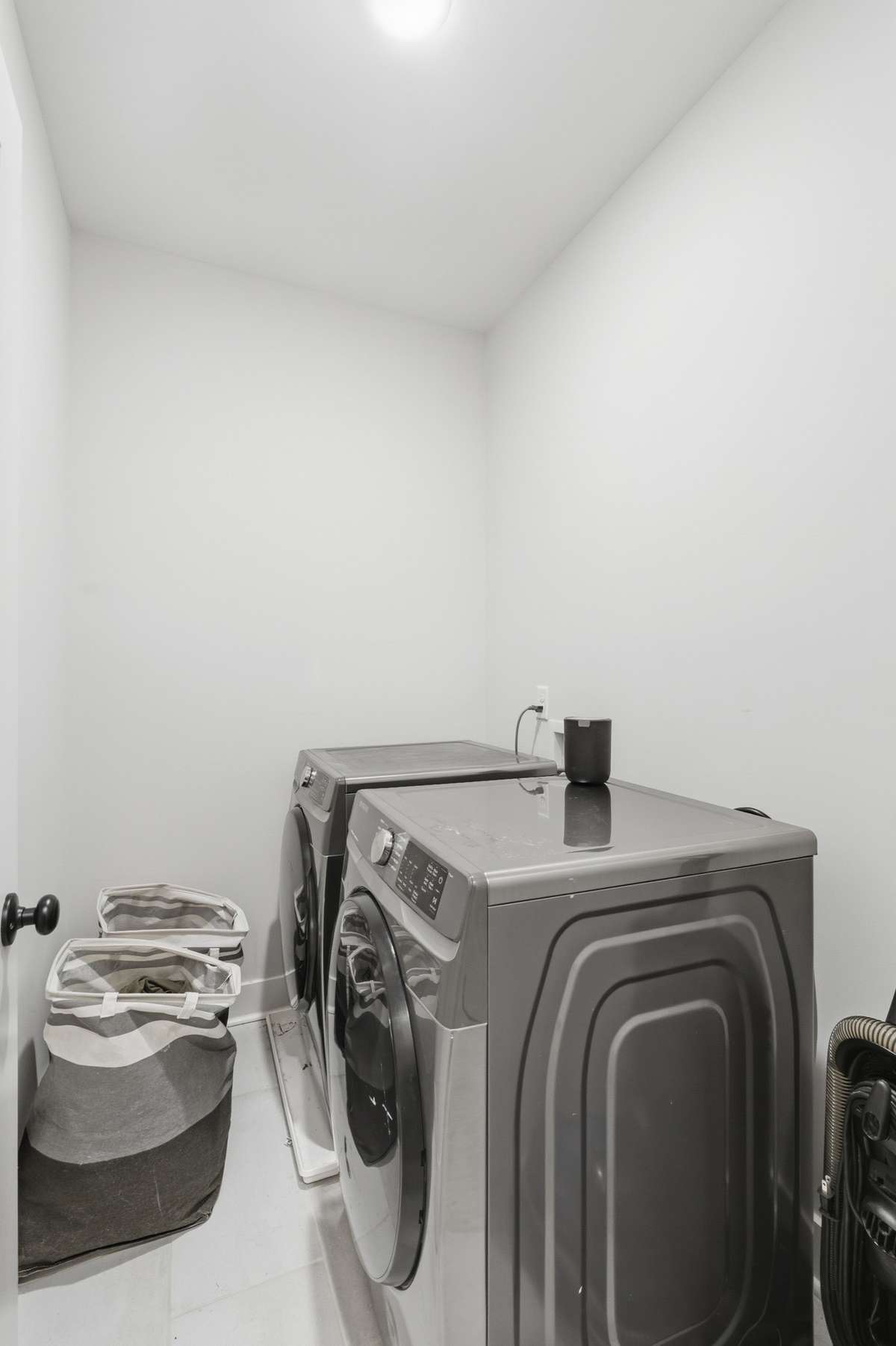 The well-organized and functional utility room, complete with custom cabinetry for storage, dedicated appliance hookups, a durable tiled floor, and a thoughtful integrated space for a pet bed creates a breath of fresh air while doing chores.