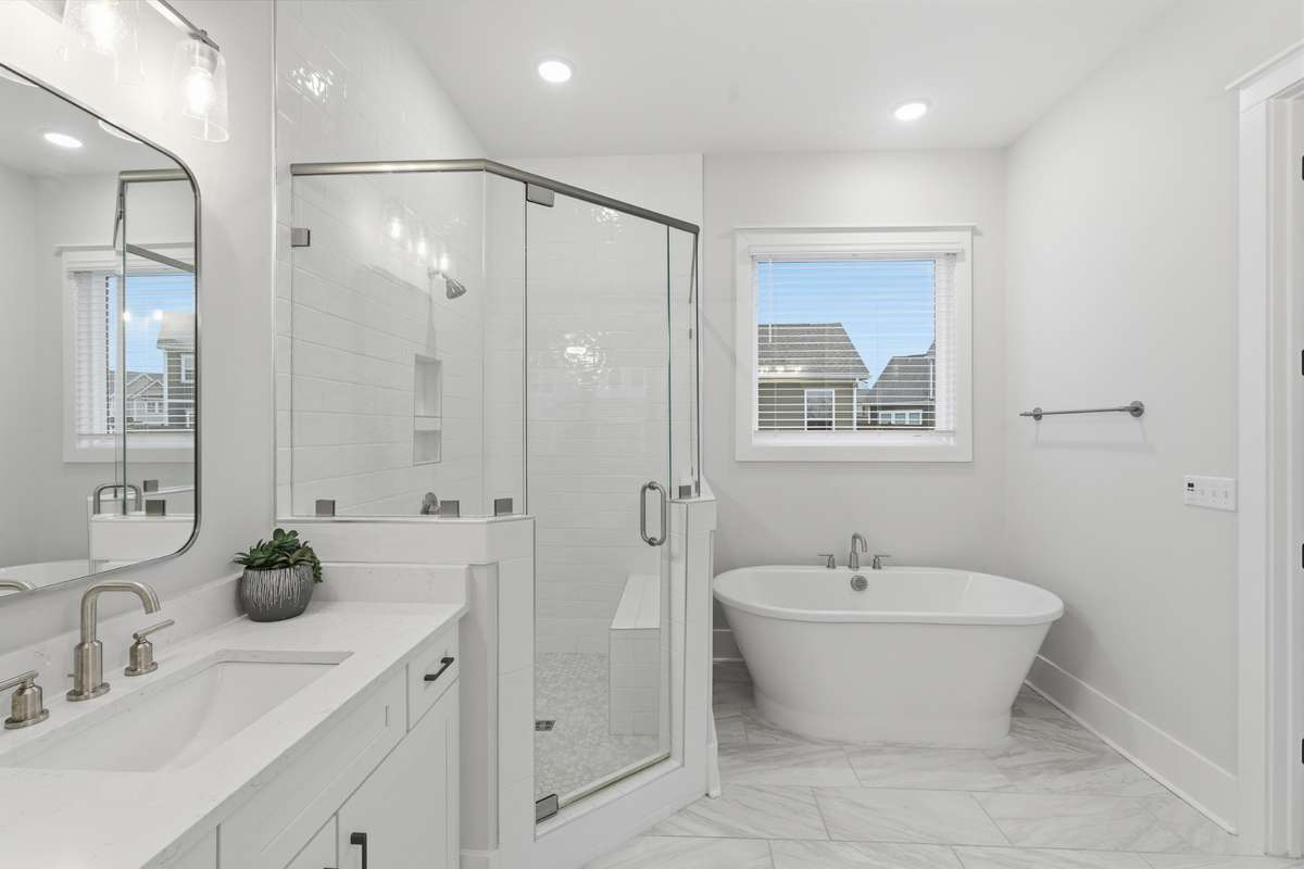 The spa like primary bathroom offers a full walk-in shower with a glass door for added warmth while also boasting a soaker tub, large sink, and a large countertop with lots of underneath cabinetry.