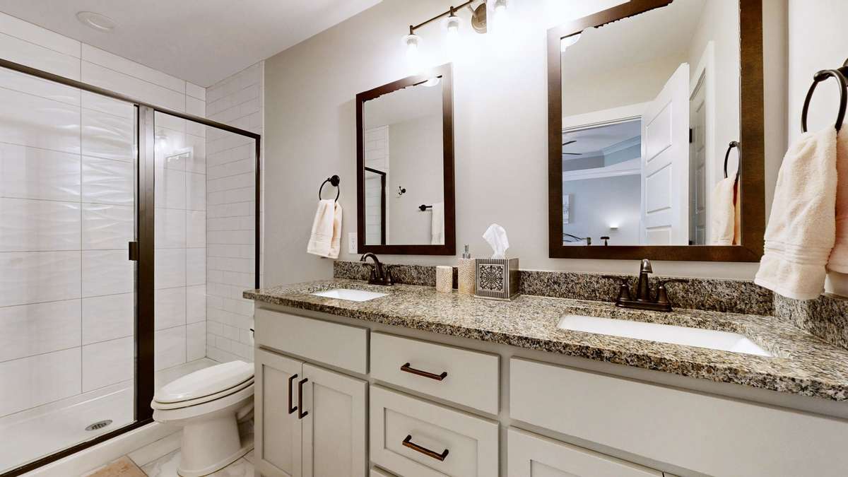 Primary bathroom with tile floor, large granite double vanity and oversized walk-in tile shower.