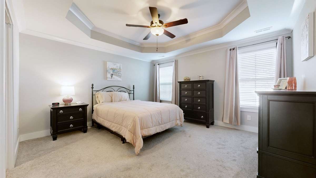 Primary suite with trey ceiling, crown molding, fan and large windows.