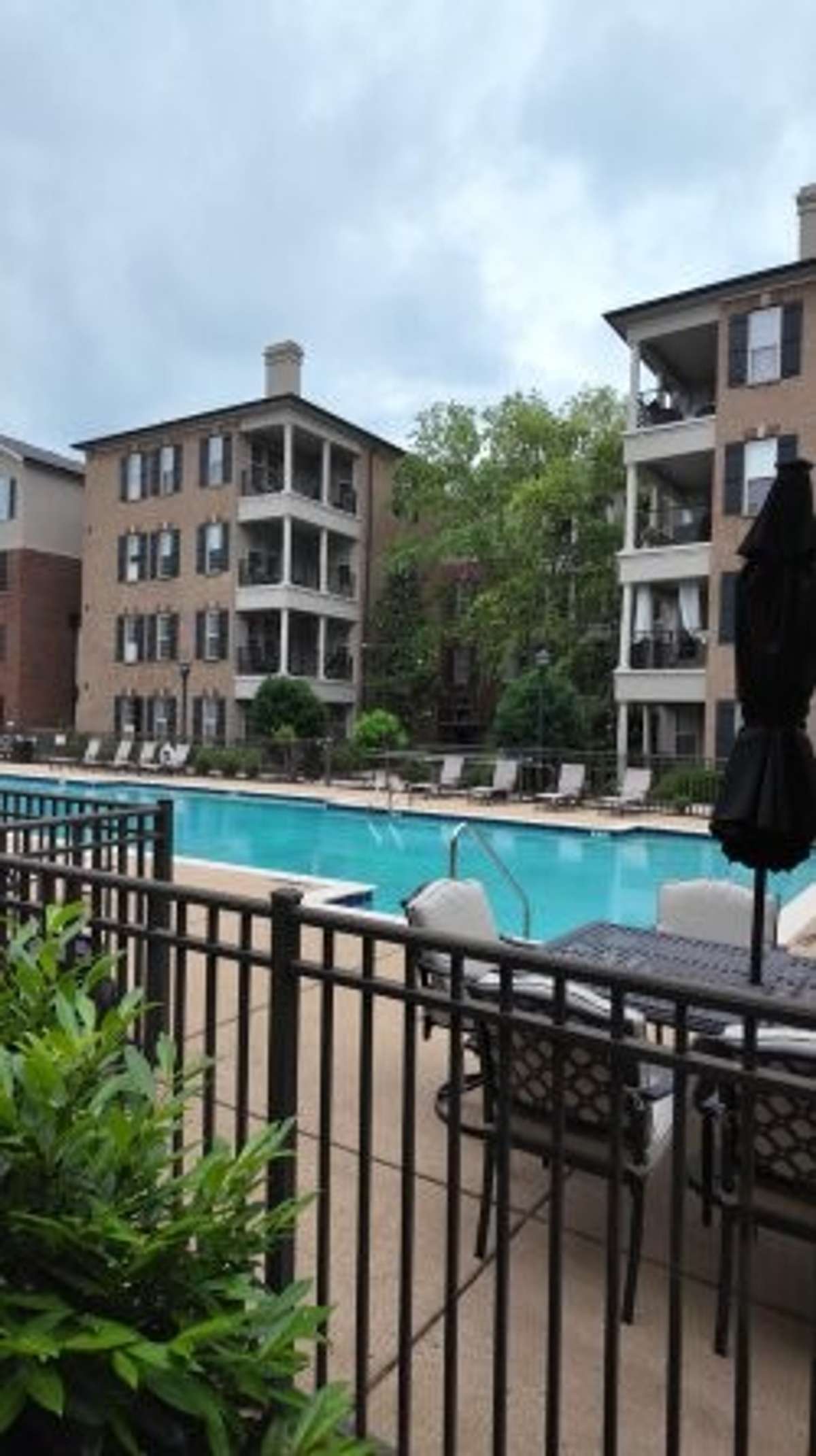 The pool area is gated and features ample and plush seating with umbrellas for shade.