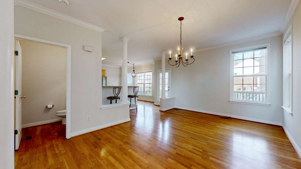 The dining room looking from the stairs towards the rear of the home.  There is a 1/2 bath to the left and you can see directly into the eat in kitchen.  Crown molding and architectural details make this home stand out.