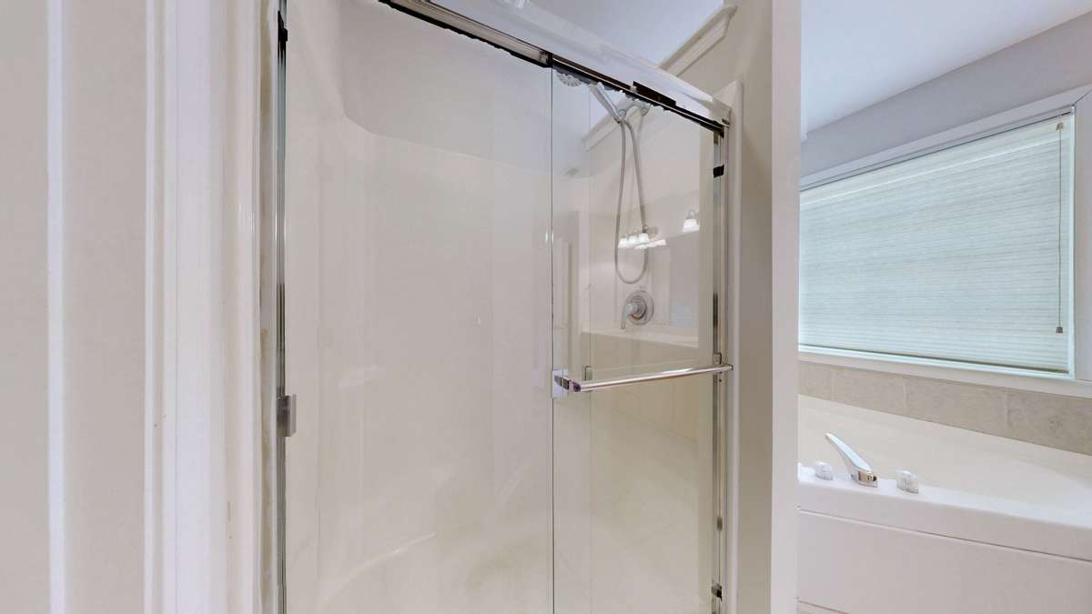 The separate shower has a brand new glass door.