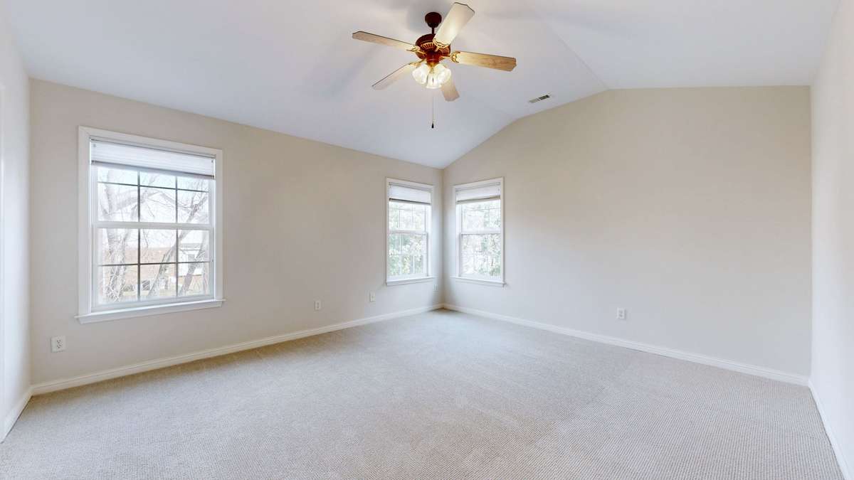 Primary bedroom with vaulted ceilings and ceiling fan.