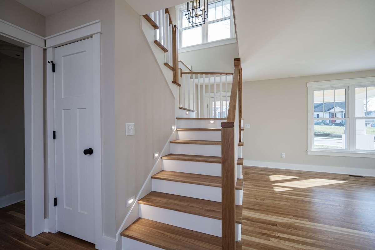 Stairway features white oak steps w/lights and a storage shelf at the top of stairs under the window.