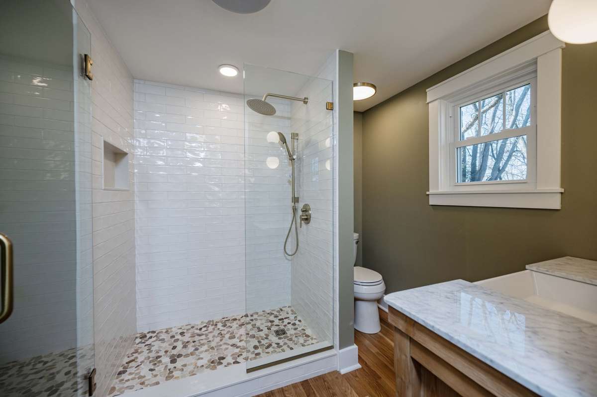 Custom tile shower floor w/ white subway tile walls. Rain shower plus handheld
