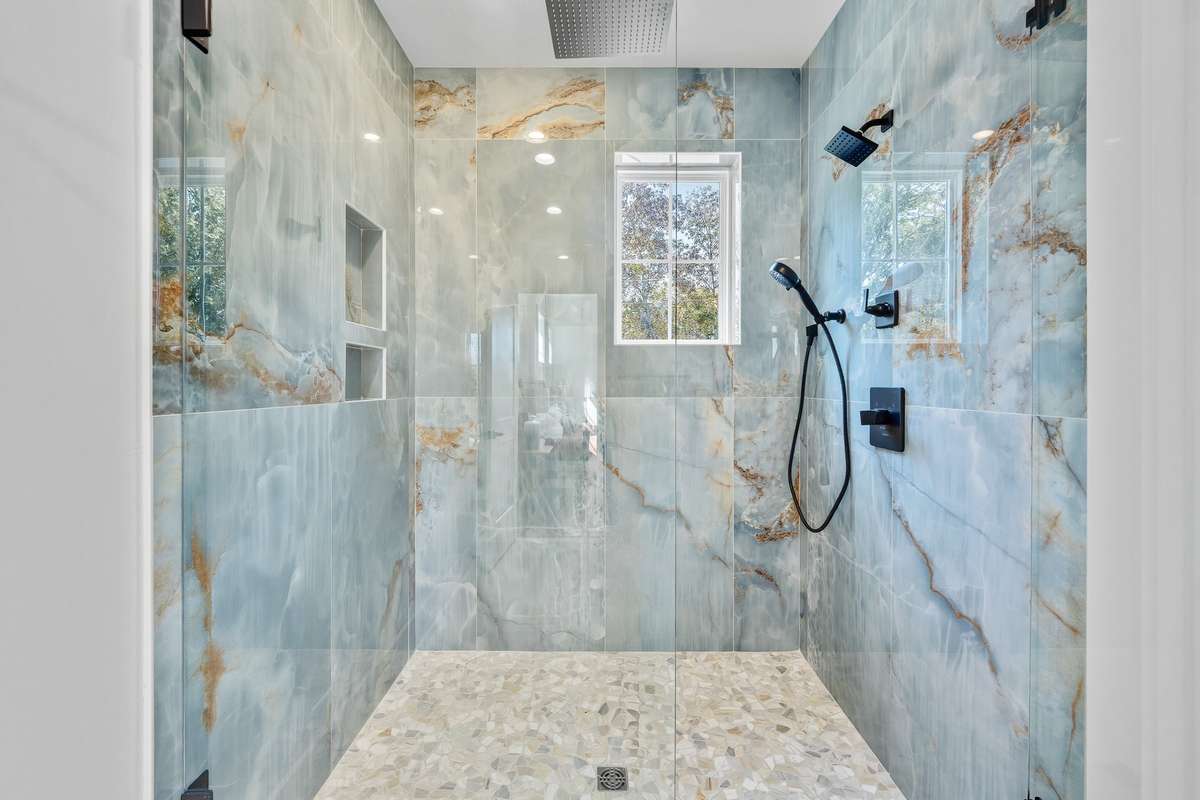 Primary Bathroom Shower – Spa-like walk-in shower with striking tile surround, rainfall showerhead, and dual niches.