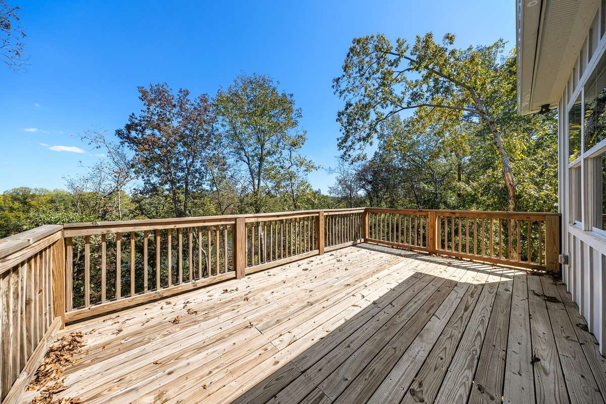 2nd Level Deck - Spacious wood deck surrounded by mature trees, ideal for enjoying fresh air and natural views.