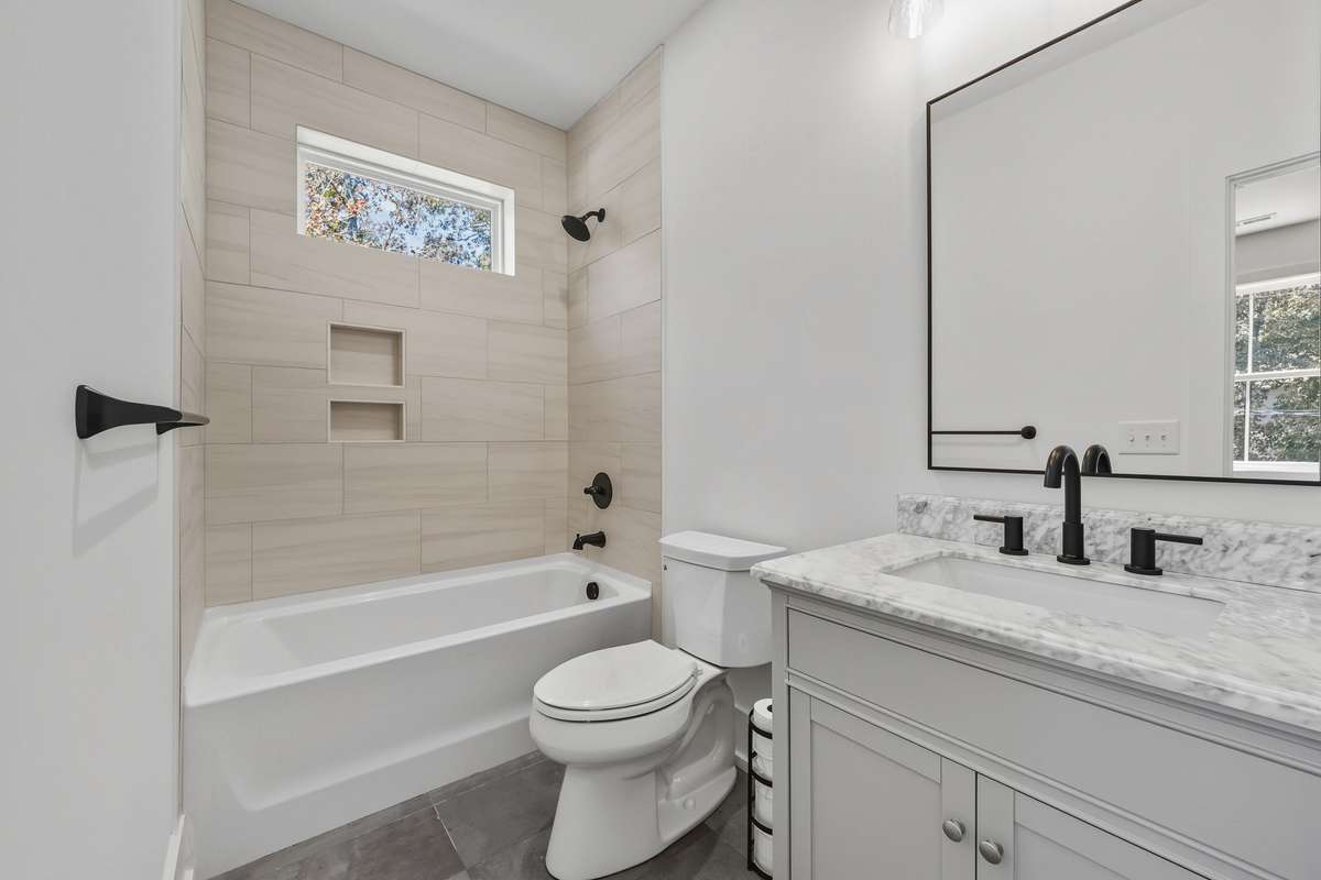 Secondary Bedroom En-suite - Full Bathroom – Elegant bath with tub/shower combo, custom tile, and marble-topped vanity.