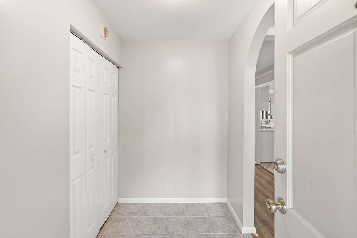 Entry foyer with a generous coat closet, fresh paint, and a charming arched doorway leading in to the main Living Room and Dining Room area.