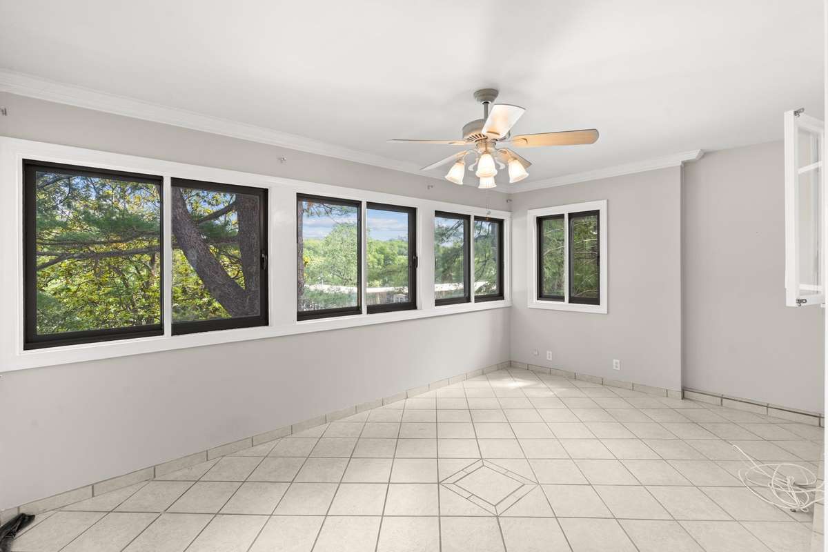 The bright Florida Room opens to the Kitchen and Dining Room. Extra windows and views of the many mature treetops offer a serene and elevated feel.