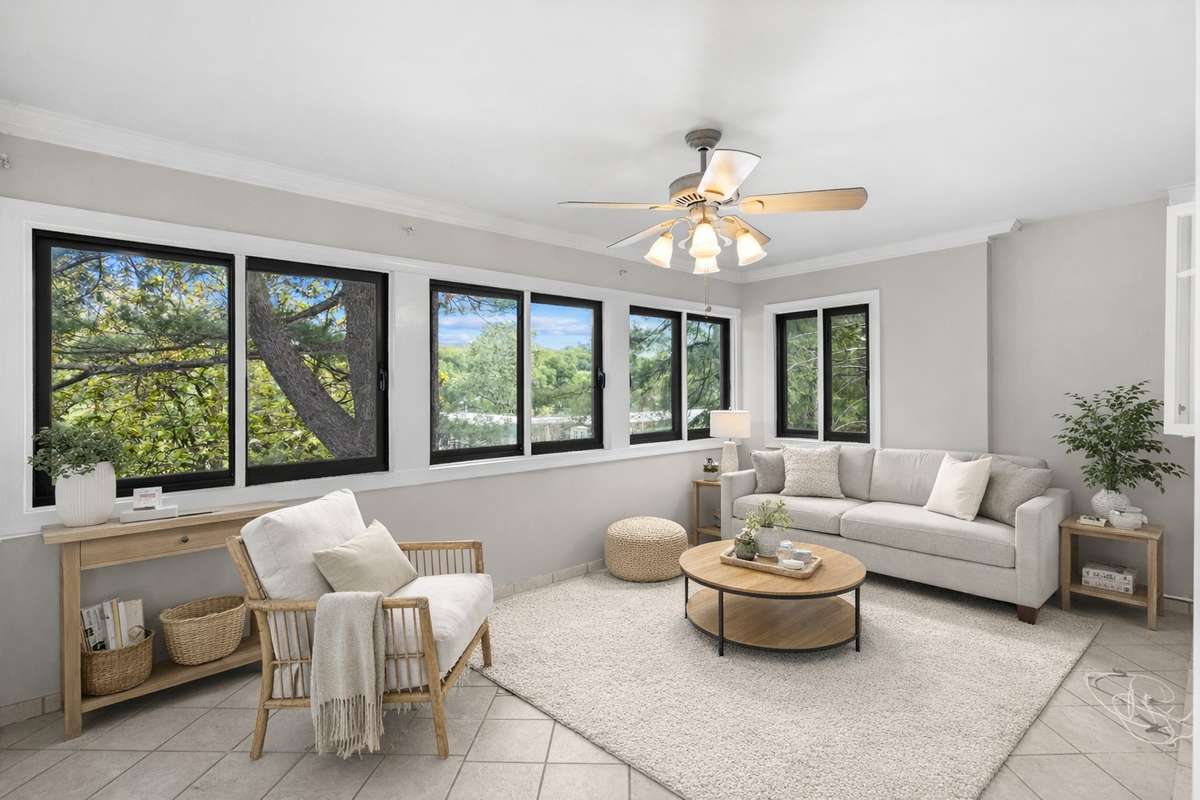 The bright Florida Room opens to the Kitchen and Dining Room. Extra windows and views of the many mature treetops offer a serene and elevated feel. Virtually staged.