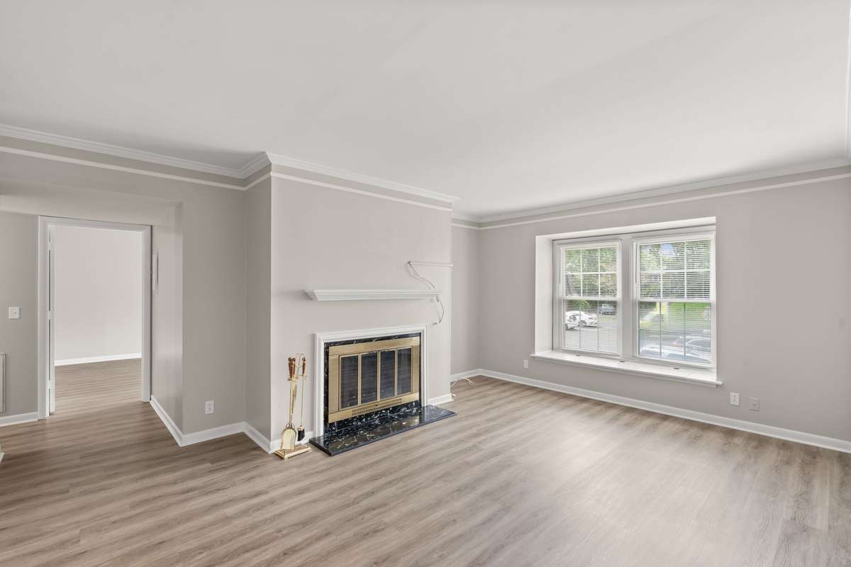Spacious Living Room with a wood-burning fireplace, fresh paint, lots of natural light, and LVP flooring. Ached doorway and crown moulding offer an elevated feel to this peaceful space.