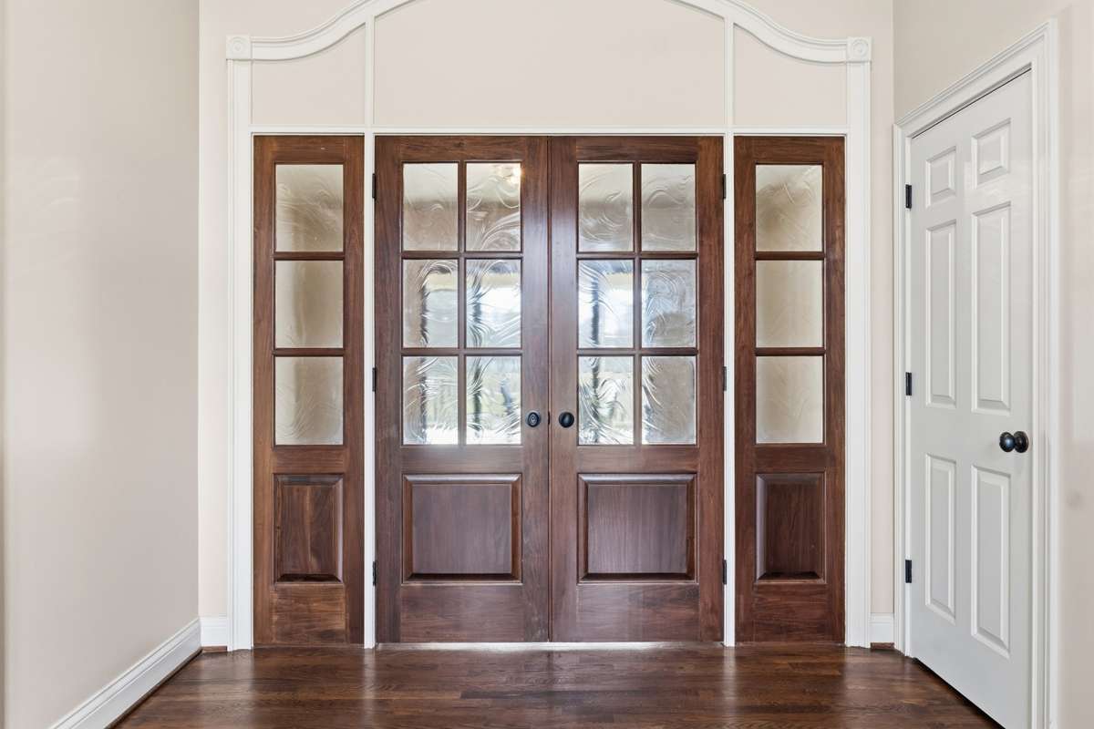 Double wooden doors with artisan glass in entry hall lead to a separate living area