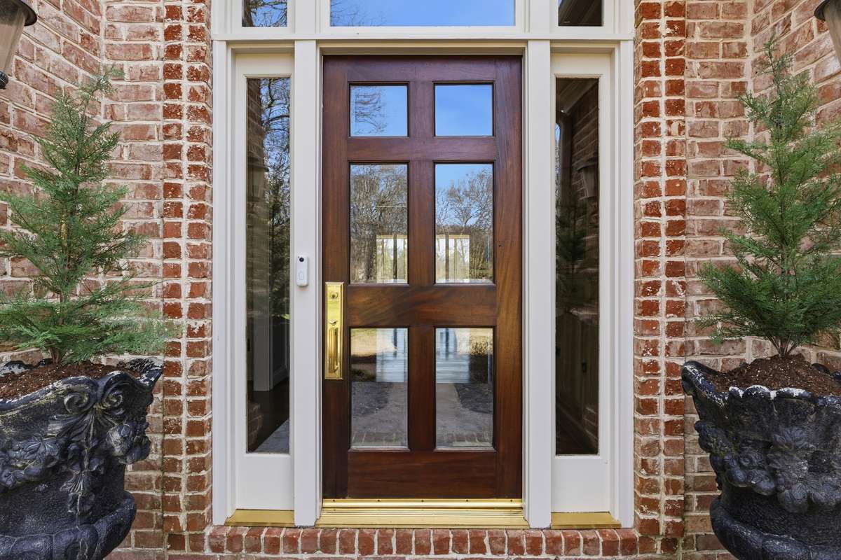 Beautiful wooden front door framed by glass panels for a sophisticated "Welcome Home"