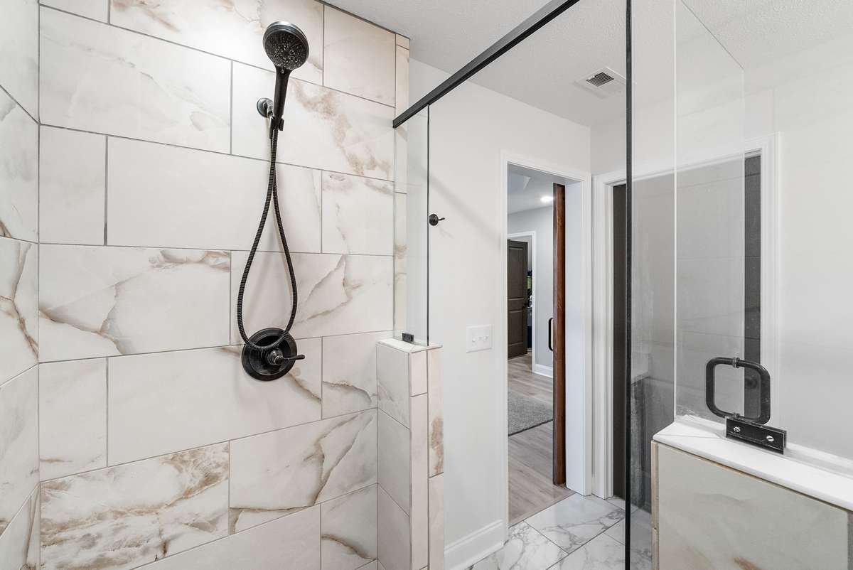 Stylish barn doors slide open to reveal another beautifully tiled en suite bathroom.