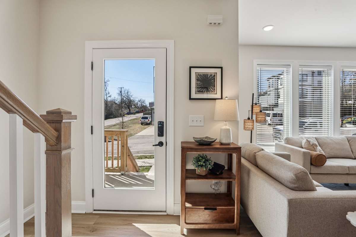 Front entry with full-glass door and immediate access to the main living space. Light-toned walls and hardwood flooring create a bright, welcoming interior.