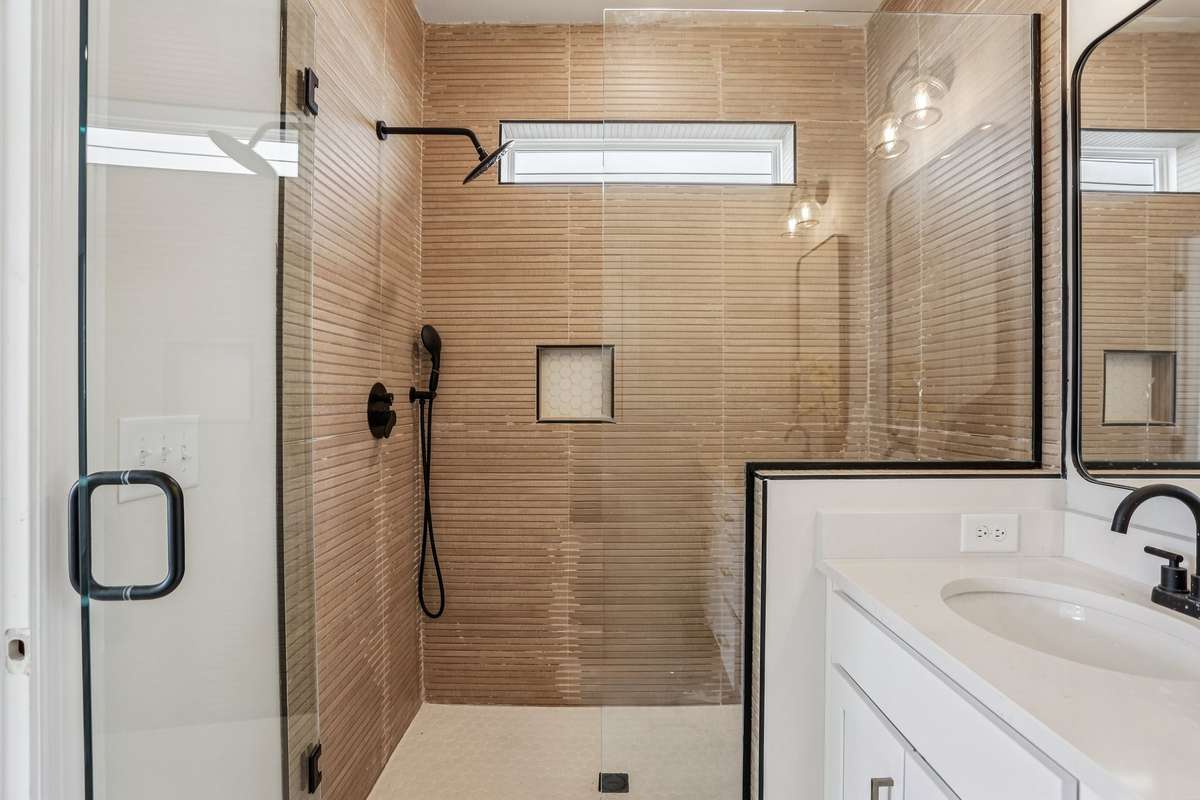 Primary bathroom with dual vanities and a glass-enclosed walk-in shower with tiled surround. The layout offers plenty of counter space and a comfortable, practical setup.