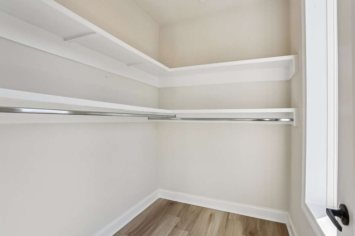 Walk-in closet with built-in shelving and hanging space, offering ample storage within the primary bedroom.