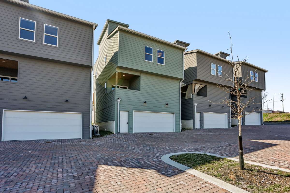The rear of the home includes an attached garage and brick-paved drive, complementing the home’s modern exterior style.